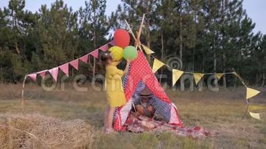 小朋友用气球和野餐毯装饰草地，在森林里的周末户外野餐