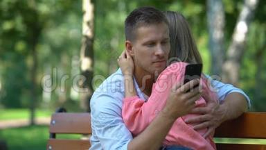 一对情侣在公园拥抱，男友给另一个女孩发短信，背叛