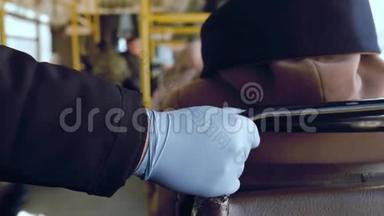 在COVID-19冠状病毒流行期间，公共<strong>交通工具</strong>中戴着橡胶手套的人手扶扶手栏杆