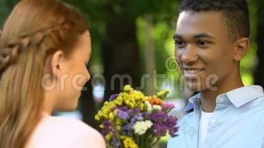 男青少年在公园给可爱的女孩<strong>送花</strong>，宣布爱情，神奇的时刻