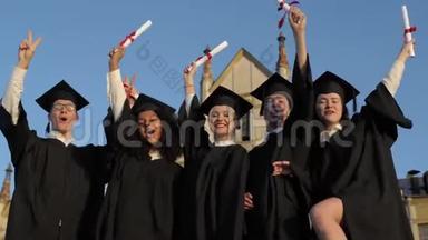 快乐的一群学生在<strong>毕业典礼</strong>上举起双臂。