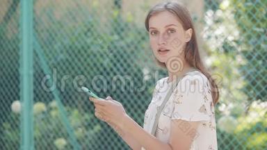 年轻白种人美丽女孩的肖像，棕色头发，蓝眼睛和雀斑使用智能手机<strong>转头</strong>和