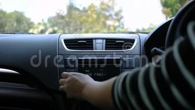 阳光明媚的一天，年轻女子开着一辆车，在车上转动收音机按钮。