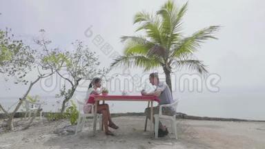 一对年轻夫妇在<strong>炎热的夏天</strong>在海滩上享受新鲜果汁。