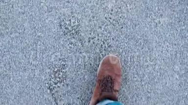 一个穿着冬靴的人在路上行走的腿的特写。