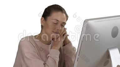 金发女孩带着粉红色的套头衫，看着<strong>电脑显示</strong>器在白色背景下观看视频。