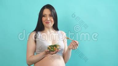 大肚子孕妇吃蓝墙隔离的蔬菜沙拉