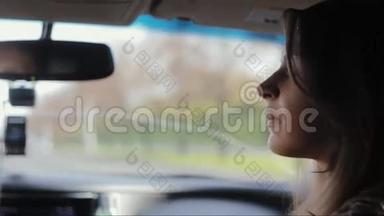 漂亮的女人坐在车里。 她看着窗外，转过头，和司机说话，开车旅行。