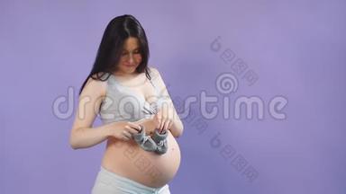 一位<strong>孕妇</strong>抱着婴儿小鞋靠近她<strong>的大肚子的</strong>肖像。