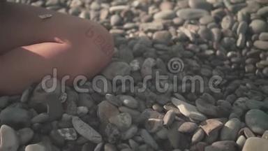 紧紧抓住一个女人的手`捡起一块石头，然后把它从海滩上的手掌上扔下来。
