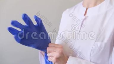 一位身穿白色制服的女<strong>医生戴</strong>上蓝色<strong>手套</strong>。 卫生、治疗、医药概念