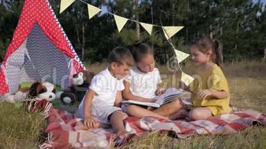 可爱的孩子们，漂亮的女孩子和快乐的男孩在森林野餐时在草地上休息的书中<strong>读故事</strong>