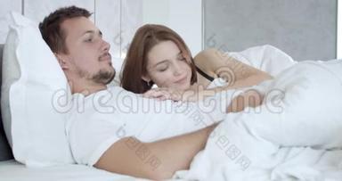 可爱的年轻夫妇躺在床上，女人躺在男人的胸膛上，4K