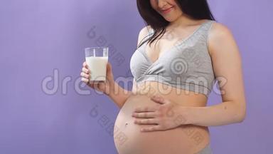 孕妇身材苗条，穿着内衣，<strong>大肚</strong>子，手里拿着一<strong>杯</strong>牛奶，隔在蓝墙上