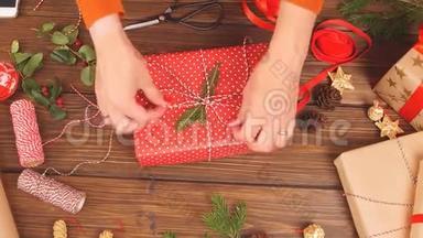 女人`手把圣诞假日手工礼物绑在手工纸上，用缠绕丝带。