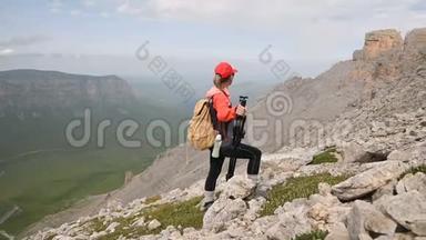 一位年轻的摄影师站在<strong>山腰</strong>上，站在高原悬崖峭壁的背景下