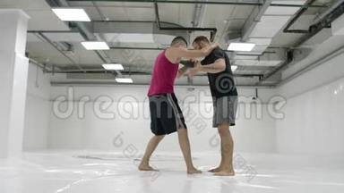 两名<strong>摔跤</strong>手动作缓慢. 希腊罗马<strong>摔跤</strong>手穿着T恤衫和外套在大厅里训练。