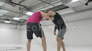 MMA战斗机练习<strong>摔跤</strong>技术。 白色大厅和榻榻米上的<strong>摔跤</strong>手。 一个穿红色T恤的男人和一个穿