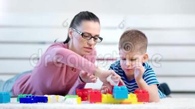 中等特写，无忧无虑，年轻的妈妈和小可爱的儿子玩<strong>建造师</strong>立方体