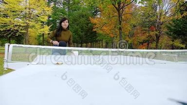 一个快乐的女人在公园打<strong>乒乓球</strong>或<strong>乒乓球</strong>，秋天