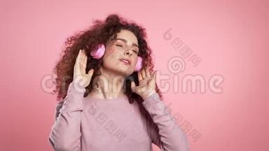 一位留着<strong>卷发</strong>、戴着耳机跳舞的漂亮<strong>女士</strong>，她在粉色工作室跳舞