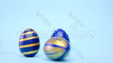复活节彩蛋<strong>滚滚</strong>，互相敲着蓝桌子.. 鸡蛋时髦的彩色经典蓝色，<strong>白色</strong>和金色。 快乐