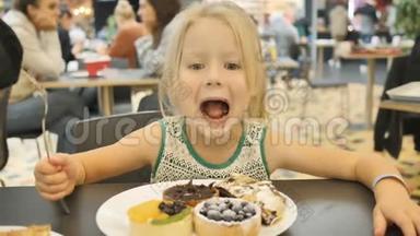 小女孩在一家背景模糊的咖啡馆里吃各种蛋糕