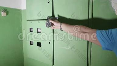 绿色电气箱的视图，上面有黑色的锁。 人`手触摸锁，并试图调整它。