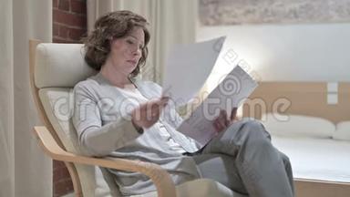 严肃的老妇人在沙发上看文件