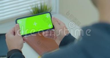 年轻人手里拿着智能手机，玩手机游戏。 带有彩色钥匙绿色屏幕的移动电话。