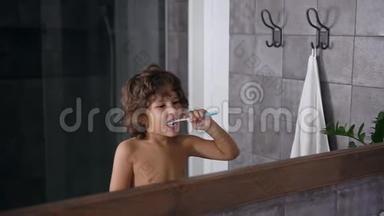 有棕色卷发的英俊小男孩在<strong>睡前</strong>或<strong>睡</strong>后刷牙时使用牙膏和牙刷
