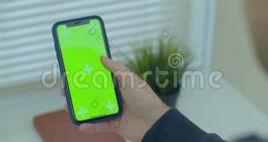 人使用垂直智能手机与绿色屏幕。 男人用手机`手的特写镜头。 铬钥匙。 快关门。