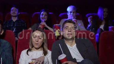 一对夫妇坐在一起看电影，看喜剧或浪漫电影。