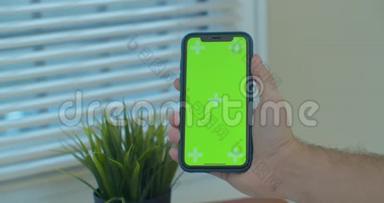 一只手握着一部移动电话，手握着一个垂直绿色屏幕的chroma关键智能手机技术。