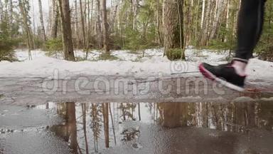 冬季公园慢跑时腿踩水坑的慢动作视图。