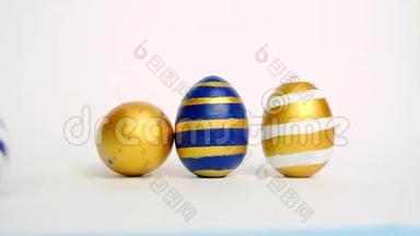 复活节彩蛋在<strong>滚动</strong>，在白色的桌子上互相碰撞。鸡蛋时髦的颜色经典的<strong>蓝色</strong>，白色和金色。快乐