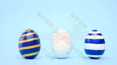 复活节彩蛋滚滚，互相敲着蓝桌子.. 鸡蛋时髦的彩色经典蓝色，白色和金色。 快乐