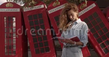 漂亮的女孩走在红色英国手机的背景上。 游，旅游地概念..