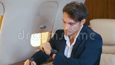 英俊的有钱人坐私人飞机飞行。 年轻自信的商人穿着西装在商务舱飞行