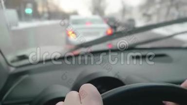 把司机的手放在方向盘上。 司机在十字路口左转。 前面的汽车视野模糊。 查看