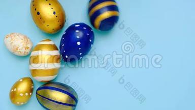 复活节彩蛋滚滚，互相敲着蓝桌子.. 鸡蛋时髦的彩色经典蓝色，白色和金色。 快乐