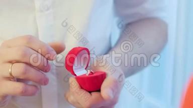 带珠宝戒指的开幕礼物。 把手举起来。 男人给女人一个红色盒子里的戒指。 与订婚戒指一起求婚