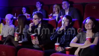 年轻的时髦朋友正在电影院看电影，他们正在吃爆米花