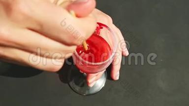 上景特写双手将红色着色剂与水混合，用高酒杯中的流苏