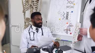 英俊的微笑着的非裔美国医生坐在医院的柜子里的桌子旁，解释的感觉