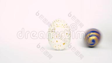 复活节彩蛋在滚动，在白色的桌子上互相碰撞。鸡蛋时髦的颜色经典的蓝色，白色和金色。快乐