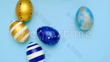 复活节彩蛋<strong>滚滚</strong>，互相敲着蓝桌子.. 鸡蛋时髦的彩色经典蓝色，白色和金色。 快乐