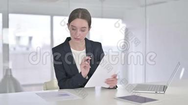 勤劳的女青年在现代办公室阅读文件