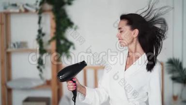 穿着<strong>白色浴袍</strong>的女人用吹风机擦干头发，慢动作