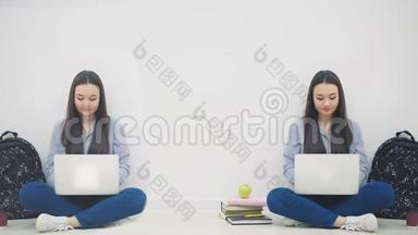 两个可爱的亚洲女孩坐在地板上，手拿笔记本电脑，点头，挥手问好，微笑。